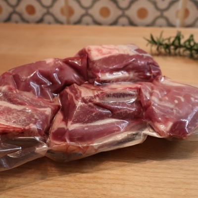 Carne crua embalada a vácuo sobre superfície de madeira com alecrim e azulejos ao fundo