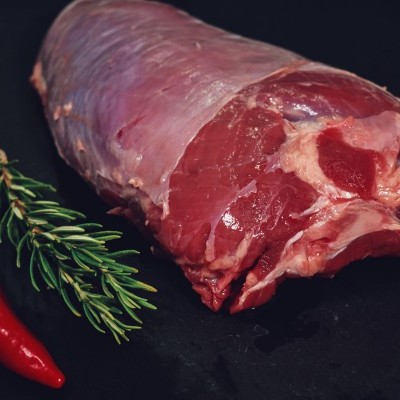 Carne crua, ramo de alecrim e malagueta vermelha sobre fundo preto