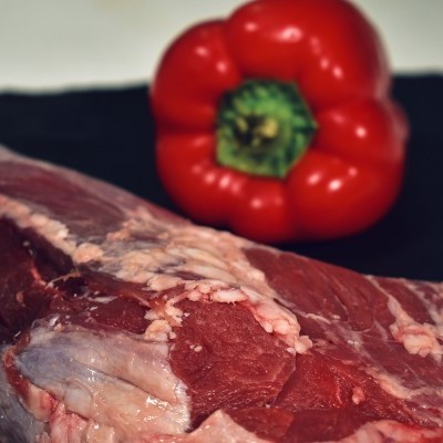 Carne crua vermelha com gordura e pimento vermelho ao fundo