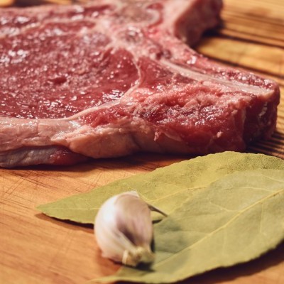 Bife cru, folha de louro e dente de alho sobre tábua de madeira