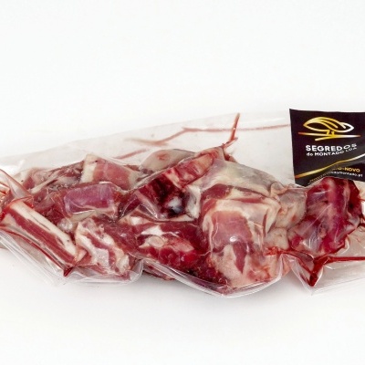 Carne embalada a vácuo com etiqueta preta e branca num fundo branco.