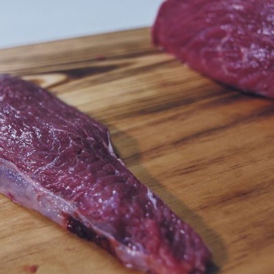 Pedaços de carne crua vermelha sobre tábua de madeira