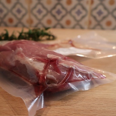 Carne crua embalada a vácuo sobre superfície de madeira com fundo de azulejos