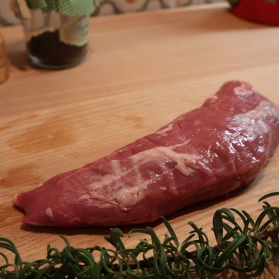 Peça crua de carne vermelha sobre tábua de madeira com alecrim