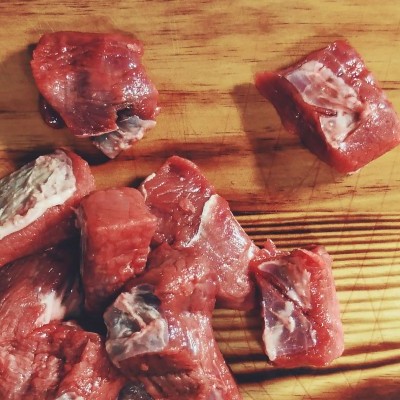 Pedaços de carne vermelha crua em tábua de madeira clara