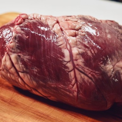 Coração cru de animal vermelho escuro sobre tábua de madeira