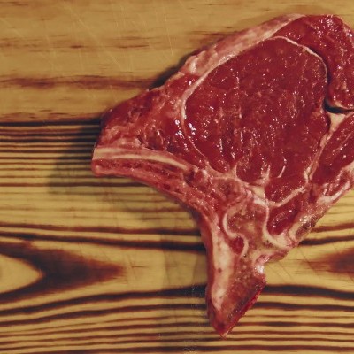 Peça de carne vermelha crua numa tábua de madeira