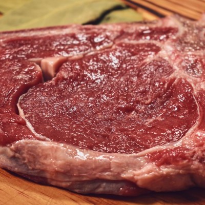 Bife cru com osso em tábua de madeira