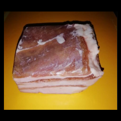 Bloco de toucinho cru com camadas de gordura e carne sobre fundo amarelo