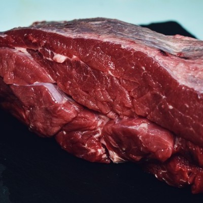 Pedaço de carne crua vermelha com gordura sobre superfície preta
