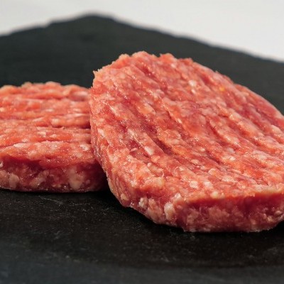 Dois hambúrgueres de carne crua sobre superfície preta