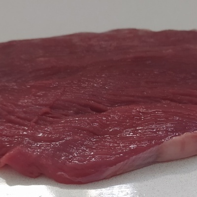 Peça de carne crua vermelha numa superfície branca