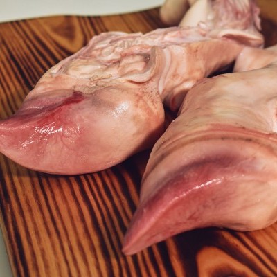 Dois pedaços de língua de porco rosados sobre tábua de madeira escura