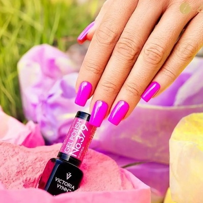 Frasco de verniz gel rosa com unhas pintadas segurando, pigmentos coloridos ao redor