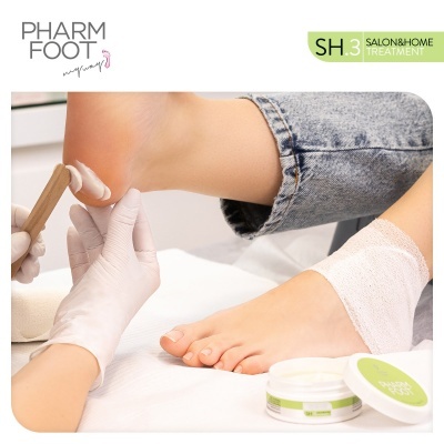 Tratamento de cuidado de pés com creme e mãos enluvadas aplicando produto PHARM FOOT