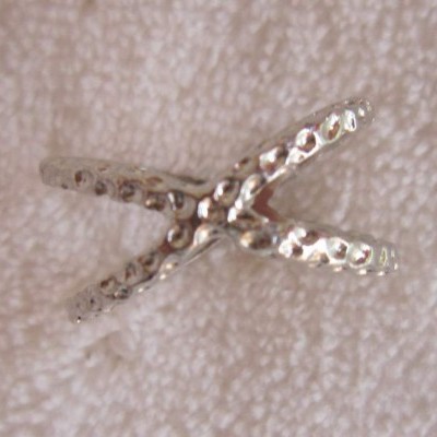 Anel metálico prateado com textura sobre tecido branco