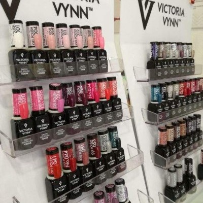 Expositores de verniz de unhas Victoria Vynn com várias cores e frascos em suportes de acrílico