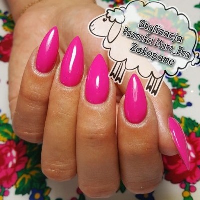 Unhas rosa brilhantes alongadas segurando recorte com texto e desenho de ovelha.