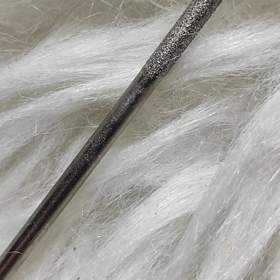 Ferramenta metálica com ponta texturizada sobre superfície branca macia