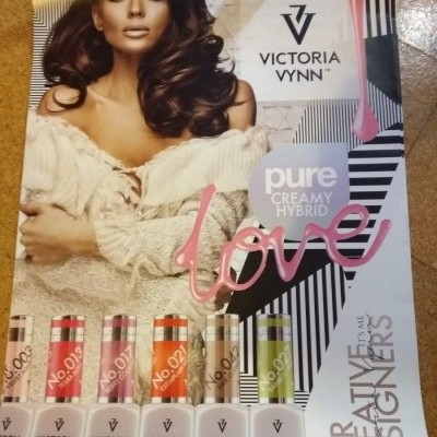 Cartaz promocional esmaltes Victoria Vynn pure creamy hybrid com seis frascos coloridos sobre fundo com modelo feminina