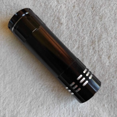 Lanterna portátil preta com detalhes prateados sobre tecido branco