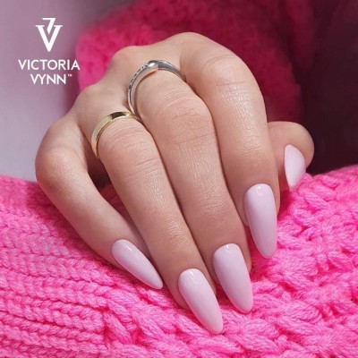 Mãos com unhas pintadas rosa claro e anéis sobre malha rosa