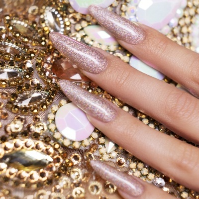 Unhas artificiais rosa cintilante em fundo bordado com pedras douradas e brancas