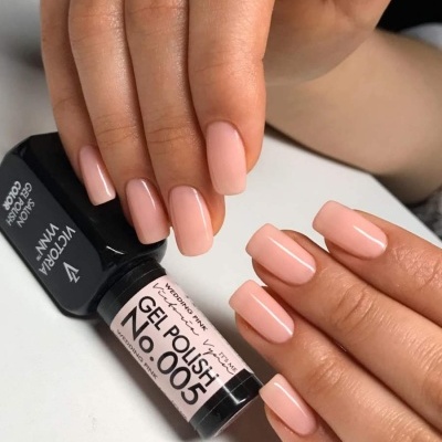 Unhas pintadas com esmalte gel rosa nude e frasco do produto