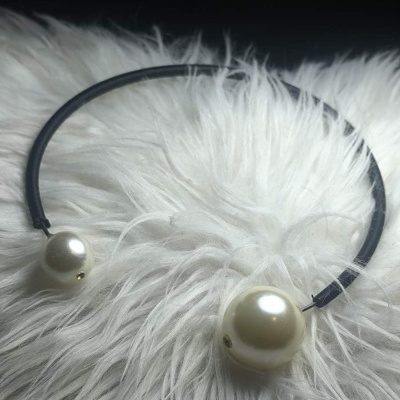 Aro para cabelo preto com pérolas brancas nas extremidades sobre tecido felpudo