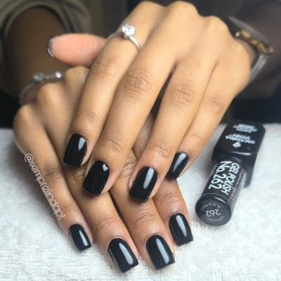 Mãos femininas com unhas pintadas de verniz preto e anel prateado
