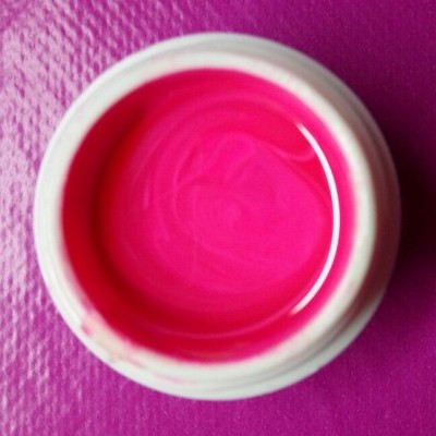 Frasco aberto com tinta rosa fluorescente em superfície rosa texturizada