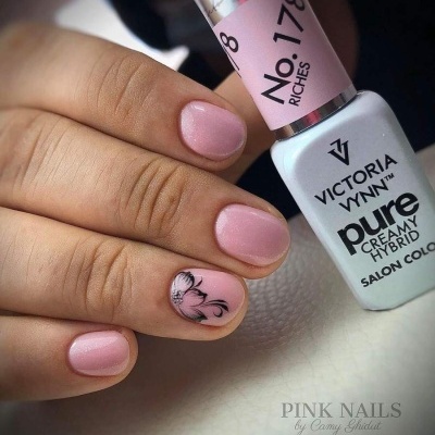 Frascos de verniz de unhas e unhas rosa claro decoradas com padrão preto numa mão