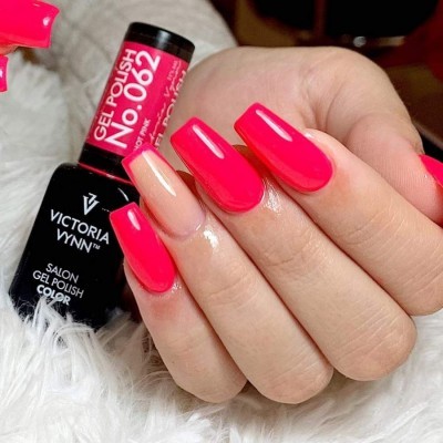 Mãos com unhas compridas pintadas de rosa vibrante com um dedo nude e frascos de verniz gel