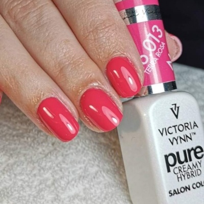 Unhas pintadas de rosa segurando frasco de verniz Victoria Vynn