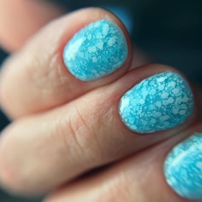 Unhas pintadas de azul claro com manchas brancas