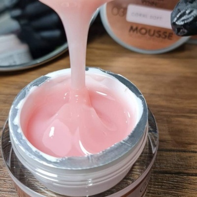 Frasco aberto de mousse cor-de-rosa claro com textura viscosa e rótulo MOUSSE