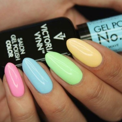 Unhas pintadas de gel em cores pastel segurando frascos de verniz gel Victoria Vynn.