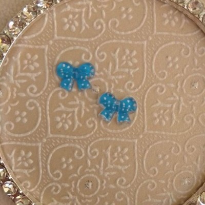 Dois laços azuis com pontos brancos sobre fundo bege com padrão e moldura com pedras brilhantes