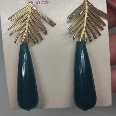 Brincos dourados com pendentes azuis escuros num cartão branco