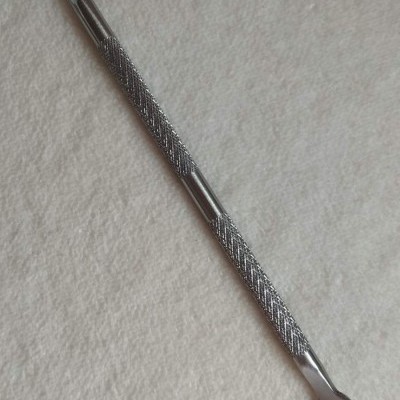 Espátula metálica dupla com cabo texturizado sobre fundo branco