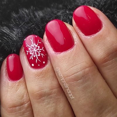 Unhas com verniz vermelho e floco de neve branco decorativo