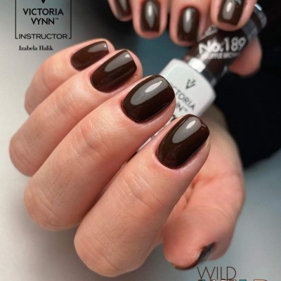 Unhas com verniz castanho escuro brilhante e frasco de verniz Victoria Vynn