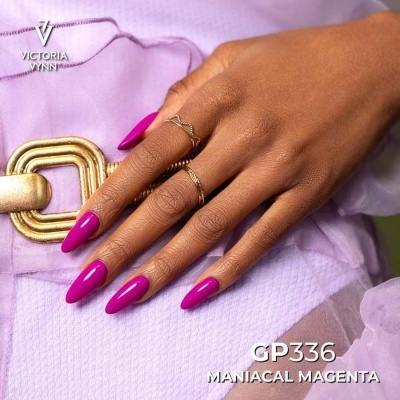 Mão com unhas magenta vibrante e argolas finas douradas sobre tecido lilás e cinto dourado.