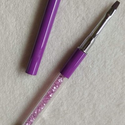 Pincel de maquilhagem roxo com cristais cor-de-rosa e ponta angular numa superfície branca