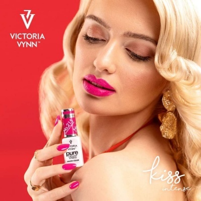 Mulher loira segurando batom rosa choque VICTORIA VYNN com fundo vermelho