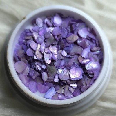 Frasco com pequenos pedaços iridescentes roxos