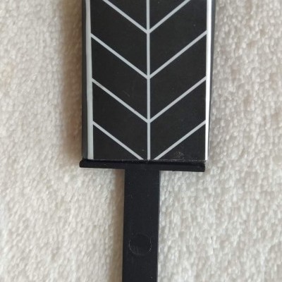 Objeto preto e branco com padrão geométrico sobre tecido branco texturizado