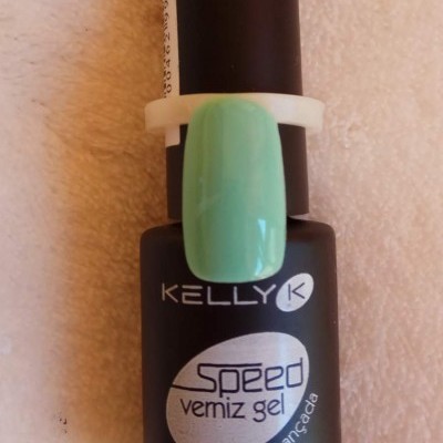 Frasco de verniz gel preto com rótulo branco e amostra de cor verde água