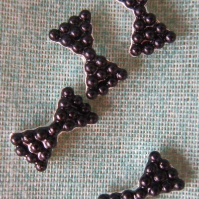 Quatro laços pretos de esferas brilhantes sobre tecido verde claro