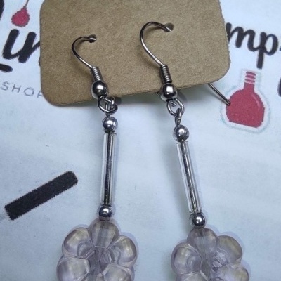 Brincos com flores translúcidas rosa e metal prateado, no cartão castanho